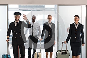 young aviation personnel team with suitcases at airport