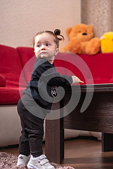 Young baby girl in black learn to walk