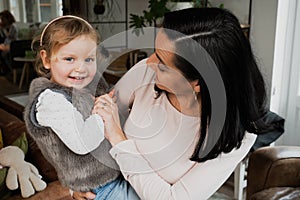 Young baby girl and her mother embrace and hug, stickling and laughter