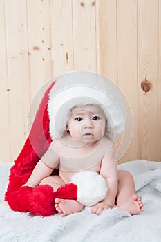 Young baby wearing a santa claus suit and hat in christmas in a barn