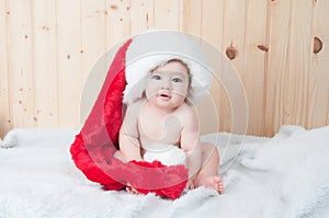 Young baby wearing a santa claus suit and hat in christmas in a barn