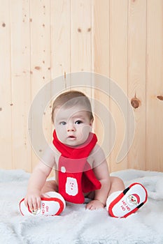 Young baby wearing a santa claus suit and hat in christmas in a barn