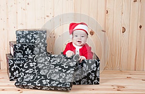 Young baby wearing a santa claus suit and hat in christmas in a barn