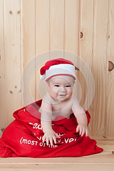 Young baby wearing a santa claus suit and hat in christmas in a barn