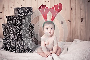 Young baby wearing a santa claus suit and hat in christmas in a barn