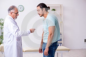 Young back injured man visiting experienced male doctor