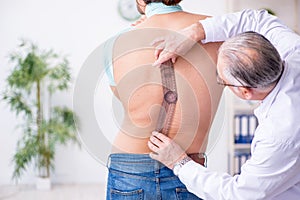 Young back injured man visiting experienced male doctor