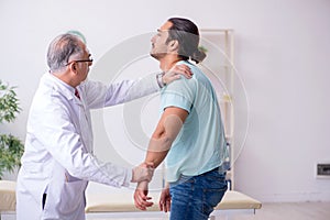 Young back injured man visiting experienced male doctor