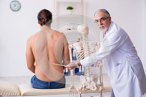 Young back injured man visiting experienced male doctor