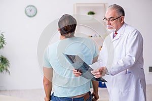 Young back injured man visiting experienced male doctor