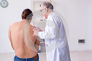 Young back injured man visiting experienced male doctor