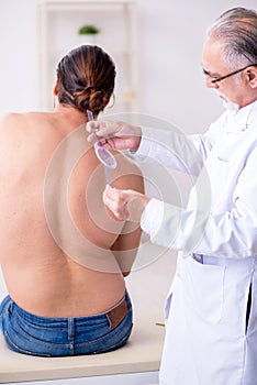 Young back injured man visiting experienced male doctor