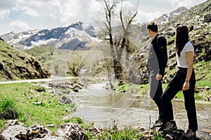 Young backpacker hiker couple enjoying relaxing mountain hike.Active hiking trip vacation.Walking by the mountain stream.Climbers