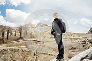 Young backpacker hiker man enjoying adrenaline mountain hike.Active hiking trip vacation.Climbing to the top of mountain cliff.