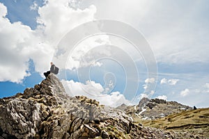 Young backpacker hiker man enjoying adrenaline mountain hike.Active hiking trip vacation.Climbing to the top of mountain cliff.