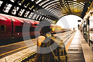 Young backpacker hipster woman waiting for the train at platform