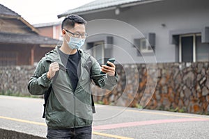 Young backpacker man is traveling alone and using smart phone with wearing mask, glasses