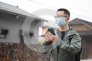 Young backpacker man is traveling alone and using smart phone with wearing mask, glasses