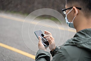 Young backpacker man is traveling alone and using smart phone with wearing mask, glasses