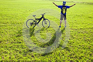 Young backpacker relaxing on a meadow with bicycle