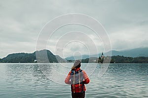 Young backpacker woman standing by mountain lake with backpack