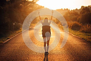 Young backpacking adventurous woman hitchhiking on the road. Ready for adventure of life. Travel lifestyle. Low budget traveling.