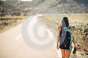 Young backpacking adventurous woman hitchhiking on the road.Traveling backpacks volume,packing essentials.Travel lifestyle photo