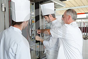 Young bakers putting unbaked bread in hot-oven in bakery