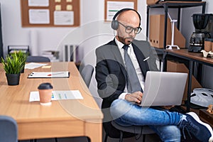 Young bald man business worker using laptop and headphones working at office