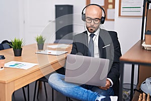 Young bald man business worker using laptop and headphones working at office