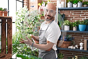 Young bald man florist using difusser working at florist