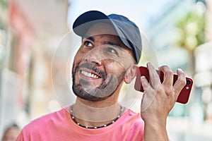 Young bald man miling confident listening audio message by the smartphone at street