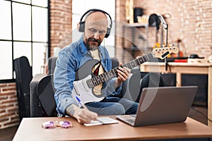 Young bald man musician composing song at music studio