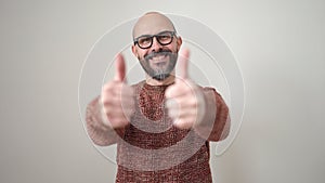 Young bald man smiling with thumbs up over isolated white background