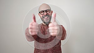 Young bald man smiling with thumbs up over isolated white background