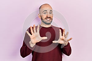 Young bald man wearing casual clothes afraid and terrified with fear expression stop gesture with hands, shouting in shock