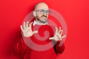 Young bald man wearing casual clothes and glasses afraid and terrified with fear expression stop gesture with hands, shouting in