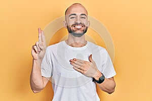 Young bald man wearing casual white t shirt smiling swearing with hand on chest and fingers up, making a loyalty promise oath