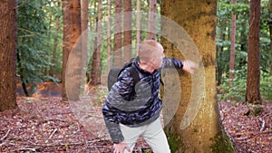 A young bald man in the woods is terrified of running away from something terrible