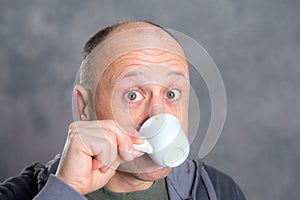 Young baldheaded man drinking coffee photo