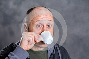 Young baldheaded man drinking coffee photo