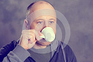 Young baldheaded man drinking coffee photo
