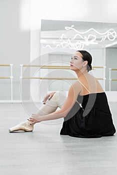 young ballerina in black dress sitting