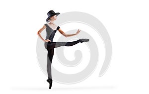 Young ballerina in black pointe shoes and an elegant hat posing on white background