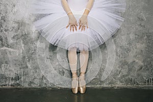 Young ballerina dancer dancing classical ballet against rustic wall