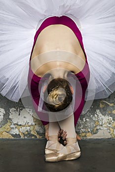 Young ballerina dancer dancing classical ballet against rustic wall