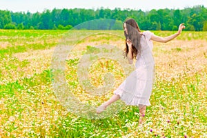Young ballerina dancing in field with daisies