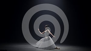 Young ballerina dancing on stage. Ballet dancer performing under spotlight.