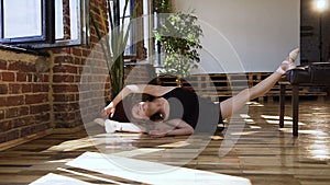 Young ballerina doing stretching sitting on a floor. Gymnast for training. Attractive girl in black tutu is doing
