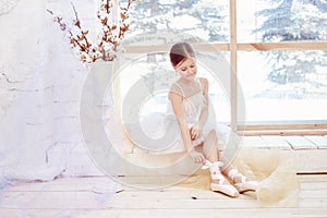 Young ballerina girl is preparing for a ballet performance. Little prima ballet. Girl in a white ball gown and Pointe